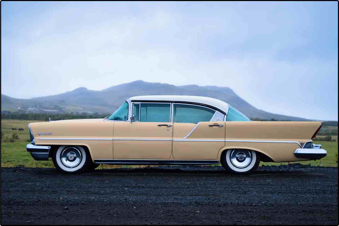 Vintage car in white and beige colors parked on a road, side perspective.